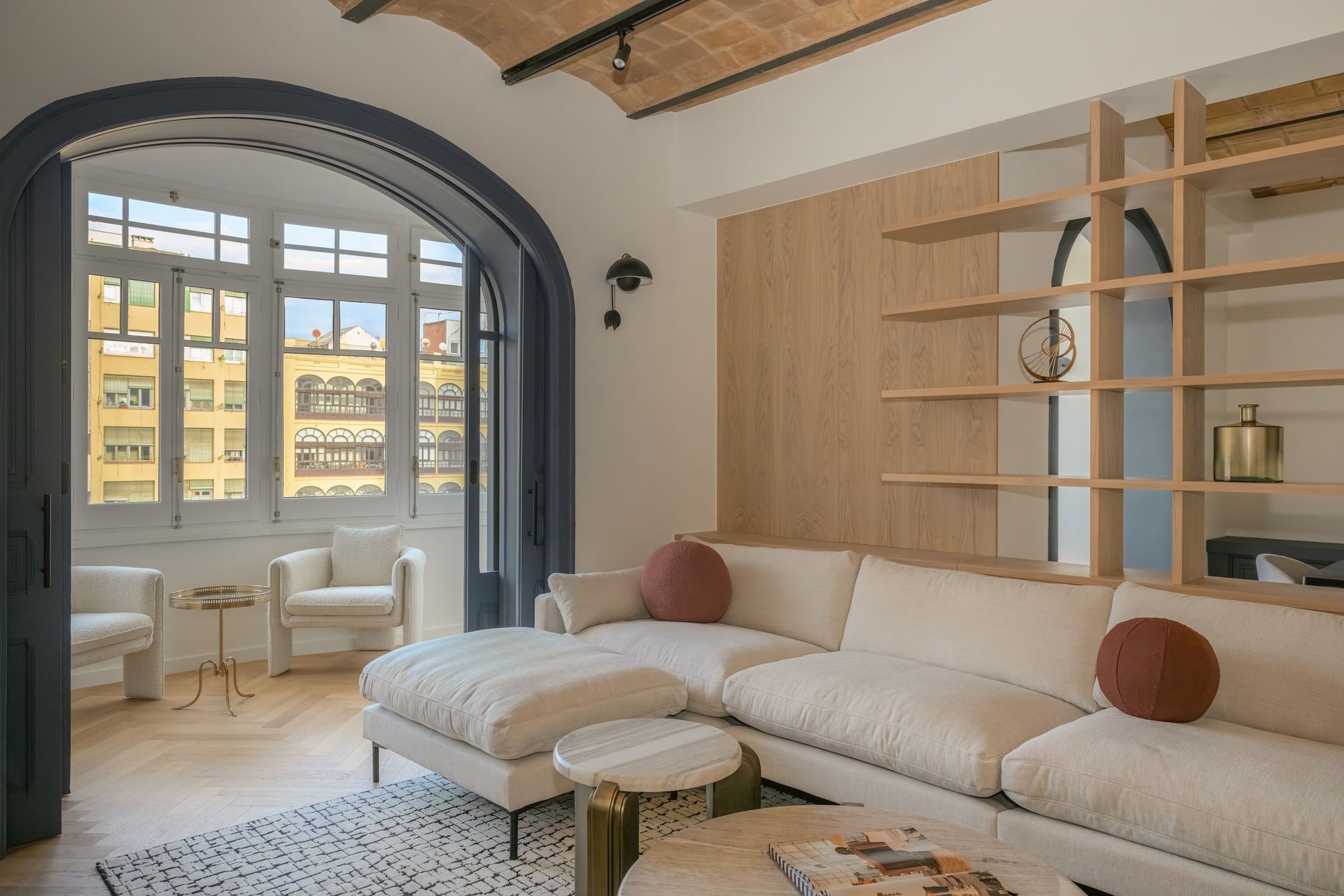 Salón con arco y librería de roble en un piso del Eixample, proyecto de BANQA en Carrer Mallorca